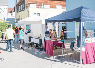 Menschen laufen an kleinen Marktständen vorbei, an dem Personen ihre Kunstwerke verkaufen.