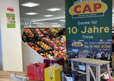 Der Tombola-Tisch im CAP-Markt mit den Hauptgewinnen und dem Aufsteller "Danke für 10 Jahre Treue".