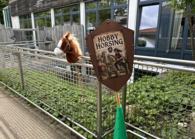Ein Wappen und ein Steckenpferd weisen den Weg in den Schulhof zum Hobby Horsing.