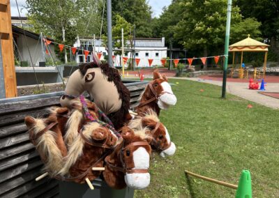 Mehrere Steckenpferde stehen im Schulhof bereit, um auf den Parcours zum Hobby Horsing geführt zu werden.